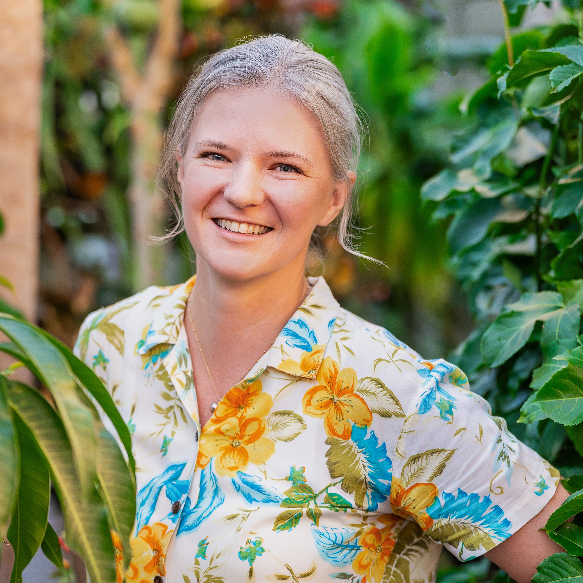 Artist Rebecca Block wearing a floral shirt in her Hawai'i backyard garden