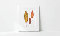 Matted artwork with Hawi'i ti leaf design on a white wall