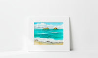 A matted watercolor painting of a beach scene with turquoise ocean waves, white clouds, and two small golden islands, displayed against a clean white wall.