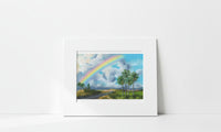 Matted artwork of a landscape with a rainbow and palm trees on a white background