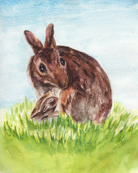 Watercolor painting of a rabbit sitting on grass with a blue sky background